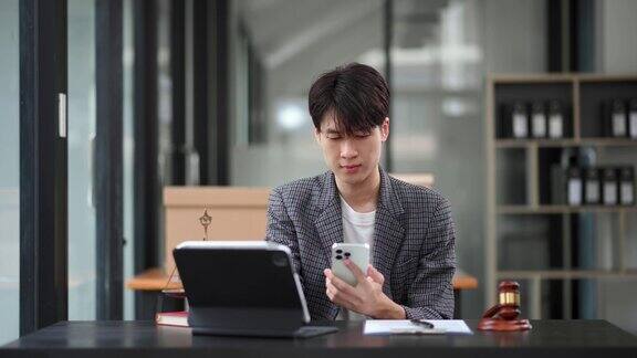 英俊的亚洲男子律师工作和木槌平板电脑笔记本电脑在前面建议正义和法律在办公室