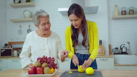 漂亮的亚洲女人在家里的厨房里和老女人做饭