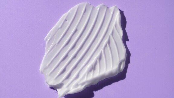 宏观的白色奶油涂抹皱纹纹理在紫色背景