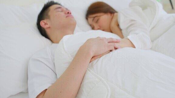 亚洲有吸引力的年轻夫妇躺在床上睡觉在卧室美丽的新婚夫妇穿着睡衣的男人和女人清晨在房子里一起躺在舒适的枕头上感到幸福和放松