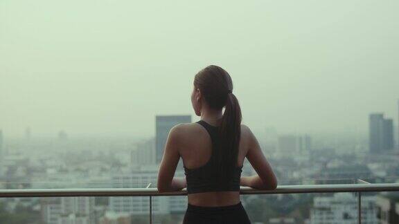 年轻女子在运动后放松眺望着城市的景色