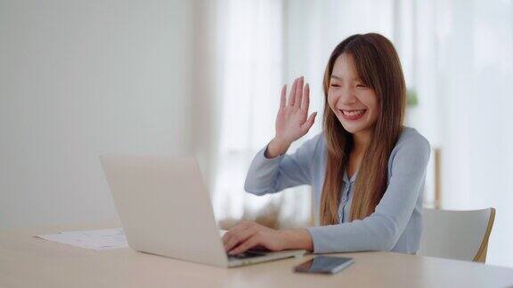 年轻的亚洲妇女在家里用笔记本电脑工作在家办公视频会议视频通话学生在线学习课堂会议会议