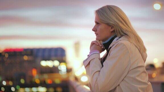 一位年轻女子倚靠在桥的栏杆上欣赏美丽的日落