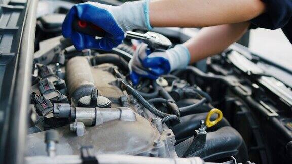 女汽车修理工用套筒扳手在车库里修理发动机