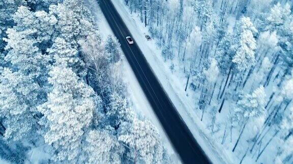 鸟瞰图一辆汽车行驶在积雪的森林道路上4k