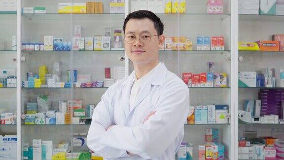 药房背景中亚洲药剂师的画像药店药剂师面带微笑望着相机用药盘清点药片分发给病人医疗保健和医疗概念