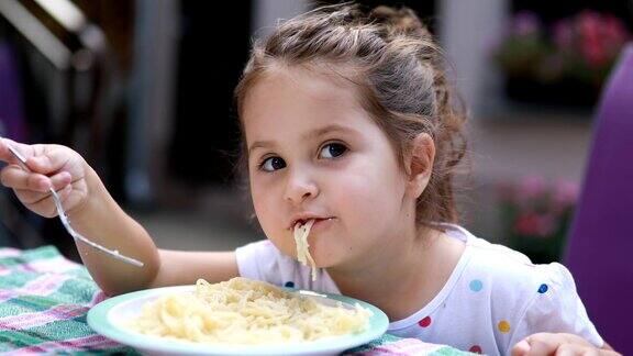 漂亮的蹒跚学步的小女孩在吃意大利面