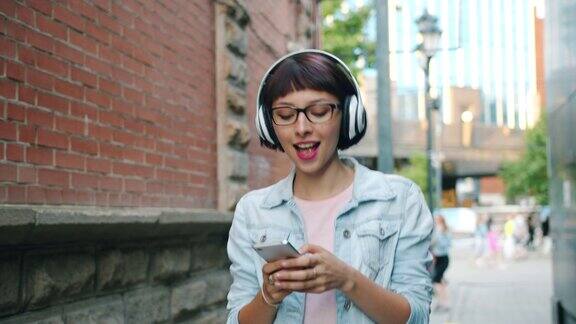 女孩在户外用智能手机用耳机听音乐的慢动作