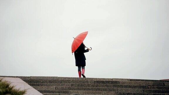 在红伞下行走的女人