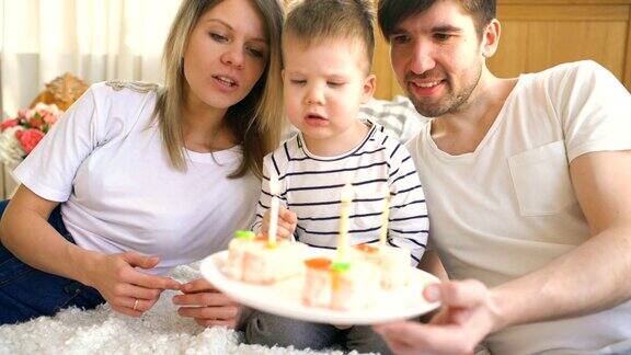一家人微笑着一起庆祝儿子的生日然后吹蛋糕上的蜡烛