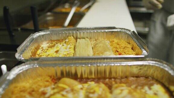 在墨西哥餐厅的商业厨房里一个人将打开的玉米粉蒸肉放入一个装有奶酪和米饭的金属烤盘里