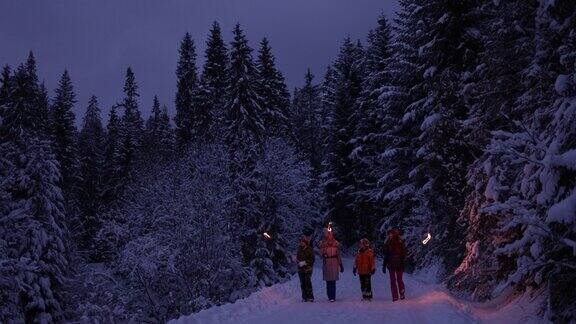 一家人拿着火把在冬天的森林里散步