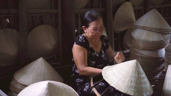 在越南Cantho省的ApThoiPhuoc村的老越南工匠制作传统越南帽子的4k镜头低光场景传统艺术家