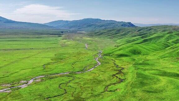 空中拍摄的新疆那拉提草原上的绿色草地、河流和山地景观