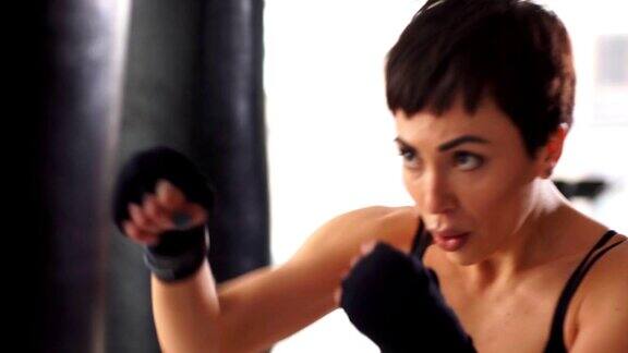 吸引人的女拳击手训练在健身房打一个沉重的袋子