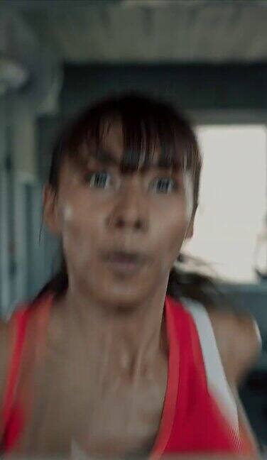 女子在跑步机上快速跑步的垂直视频