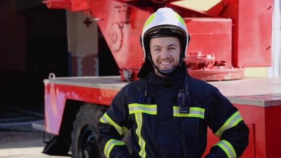 幸福的消防员肖像与头盔附近的消防车执勤的消防员画像