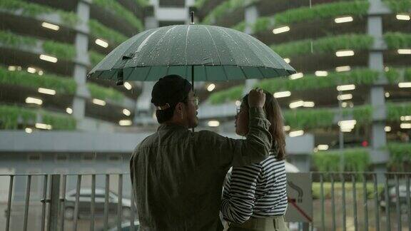 一对亚洲夫妇在下雨天打着伞一起散步
