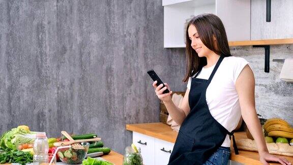 微笑的家庭主妇聊天用智能手机烹饪食欲健康的食物在厨房