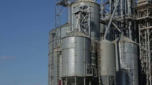 现代粮食码头电梯的金属罐谷物干燥复杂的建筑港口的商业谷物或种子仓库农用钢材储运浮云在天空