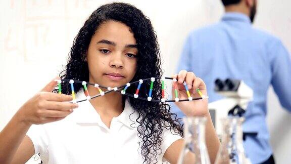 混血中学生在检查DNA螺旋模型时做笔记