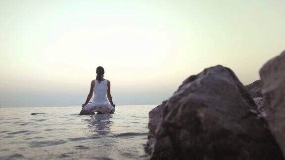 在海中岩石上沉思的女人