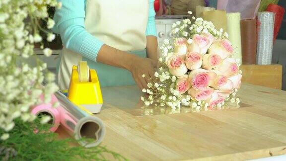 花店花匠用玻璃纸包住玫瑰花束