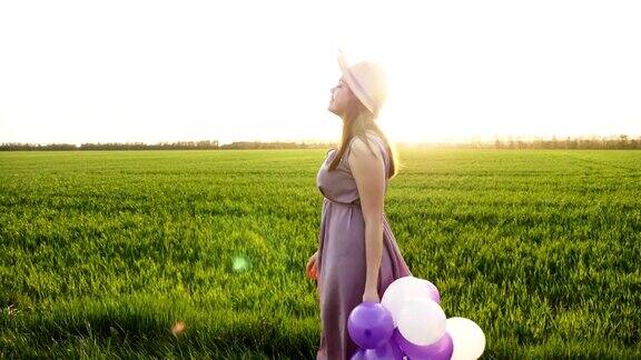 美丽的女孩拿着五颜六色的气球走在春天的田野上