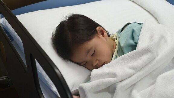 生病的小女孩睡在床上孩子在发烧妇女抚摸着孩子的头在医院