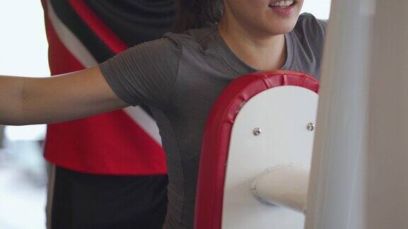 亚洲妇女在健身房和教练做重量训练
