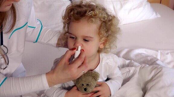 儿科医生医生用鼻喷雾剂治疗鼻塞可爱的女孩病人
