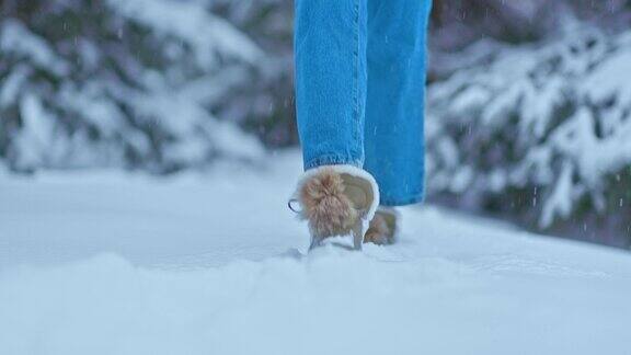 特写镜头穿着靴子和牛仔裤的脚在雪地里走着踩着倒在雪地里女人的双脚走在森林里铺满雪的小路上4kProRes