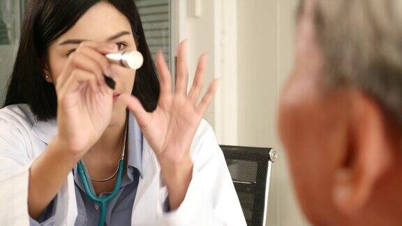 医生在医务室用手电筒检查老男病人的眼睛