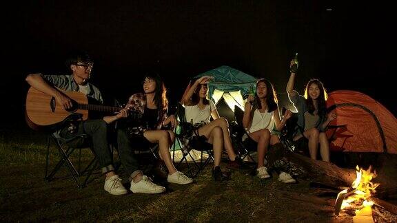 群朋友在露营旅行中唱歌和喝啤酒