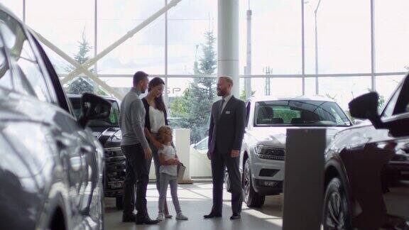 家庭购买汽车与销售人员在汽车展厅握手