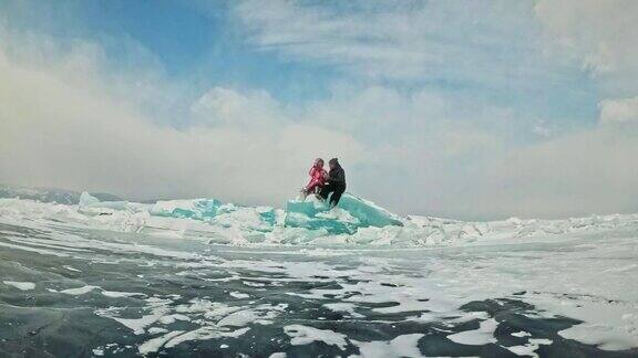 年轻的夫妇有乐趣在冬季散步的背景冰冻结的湖情侣们坐在巨大的蓝色浮冰上亲吻拥抱从热水瓶里喝着茶爱情故事