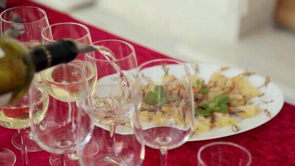 在宴会上侍者把白葡萄酒倒进玻璃杯里