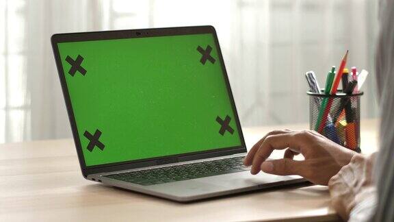 使用笔记本电脑的人在家里的桌子上绿色屏幕