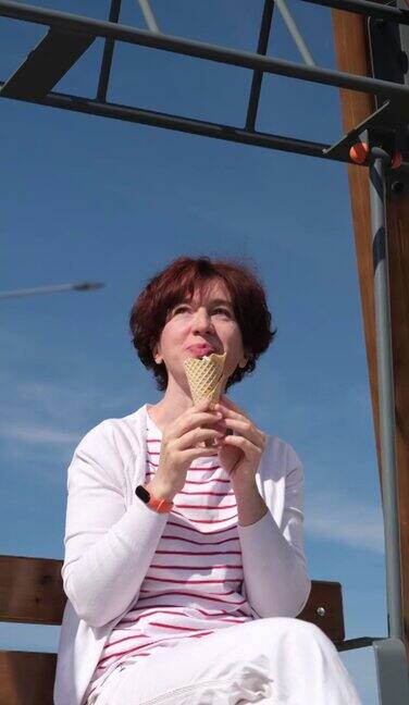 一个女人坐在城市街道的摇椅上享受着冰淇淋蛋筒