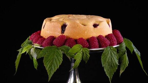 自制的覆盆子饼干放在银蛋糕架上用新鲜的浆果和树叶装饰