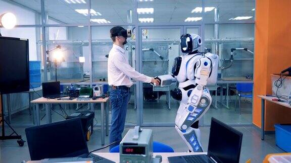 男工人和机器人在一个房间里握手虚拟现实游戏