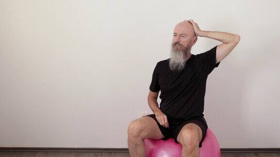 男子坐在健身球上做静态颈椎运动