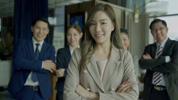年轻的亚洲自信的商业女性的肖像站在会议室看着相机交叉她的手臂和微笑
