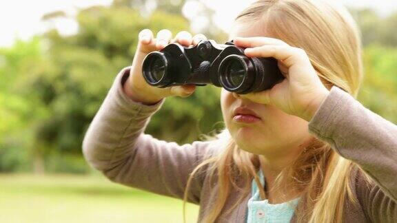可爱的小女孩在公园里用望远镜