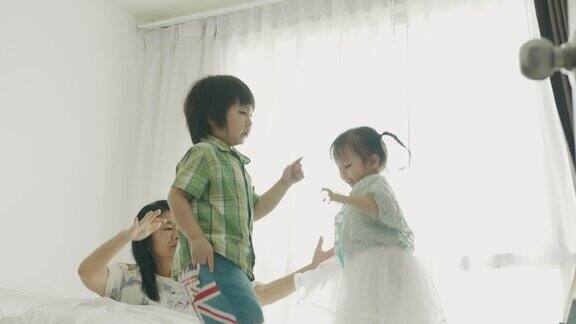 泰国小弟弟和妹妹在床上跳舞和跳他的妈妈在他们的房间