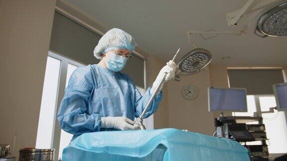 一名戴着防护口罩的女性医护人员站在手术器械旁的肖像外科器械手持手术器械的外科医生腹腔镜检查做准备