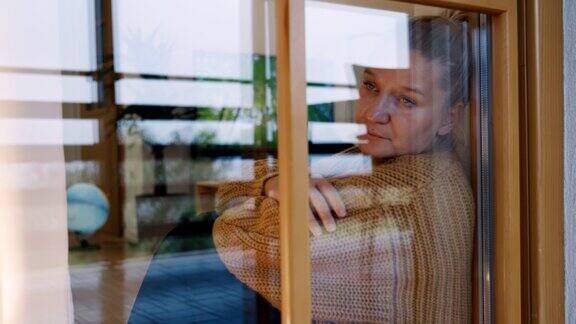 忧郁的女人透过她家的窗户往外看