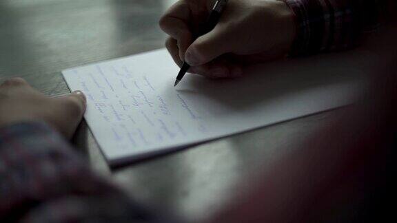 Kuchl奥地利-2019年8月22日:一名男子在棕色木桌上的白纸上书写信件复古信婚礼爱情故事新郎誓言缓慢的运动关闭了