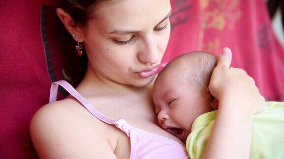 小男孩睡在妈妈的胸口上母亲把睡着的婴儿搂在怀里轻轻地吻着孩子