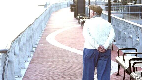 一位老人在城市海滨散步